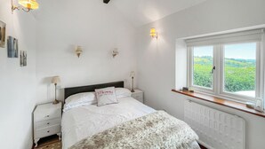 A bedroom with a bed, bedside lamps, a window with a view, and a radiator. - Henfaes Bwthyn - UK50266 (Nannerch, near Clwydian Range)