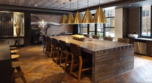 A modern kitchen with a large island, bar stools, pendant lighting, and a view of the outdoors. - Renew Tanglewood 3-bedroom in Uptown Houston (Houston)