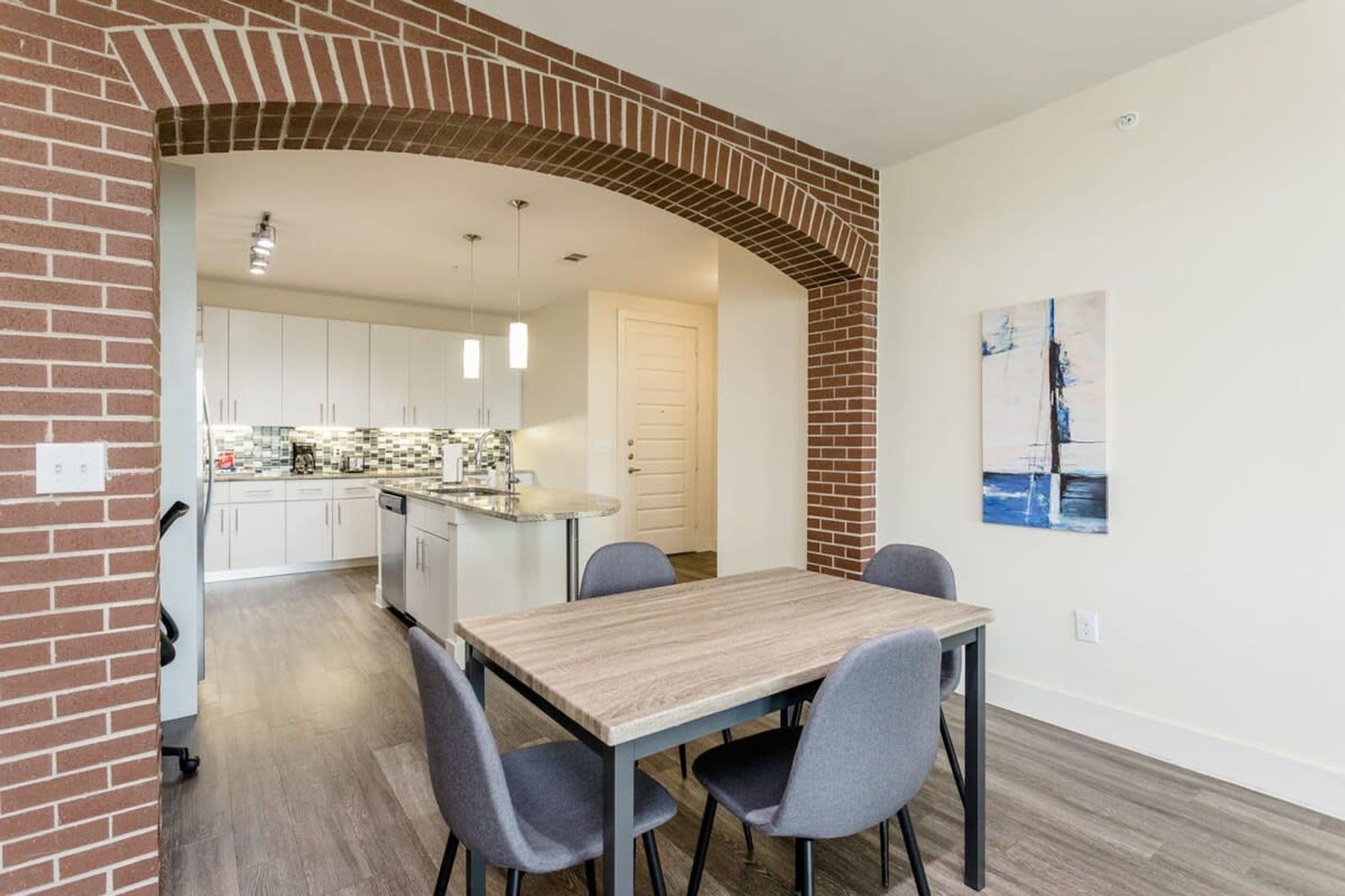 A dining area with a brick archway leading to a kitchen.