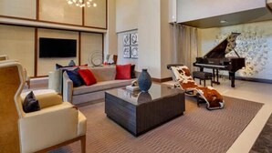 A modern living room with a sofa, armchair, coffee table, and a grand piano. - The Preston Charm I Premium 1BR in Dallas (Dallas)