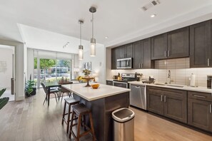 A modern kitchen with dark cabinets, stainless steel appliances, and a central island with stools. - The Preston Charm I Premium 1BR in Dallas (Dallas)