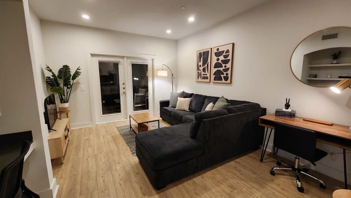 A modern living room with a sofa, a desk, and a mirror.