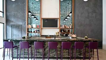 A bar area with a marble countertop, purple bar stools, and pendant lighting.