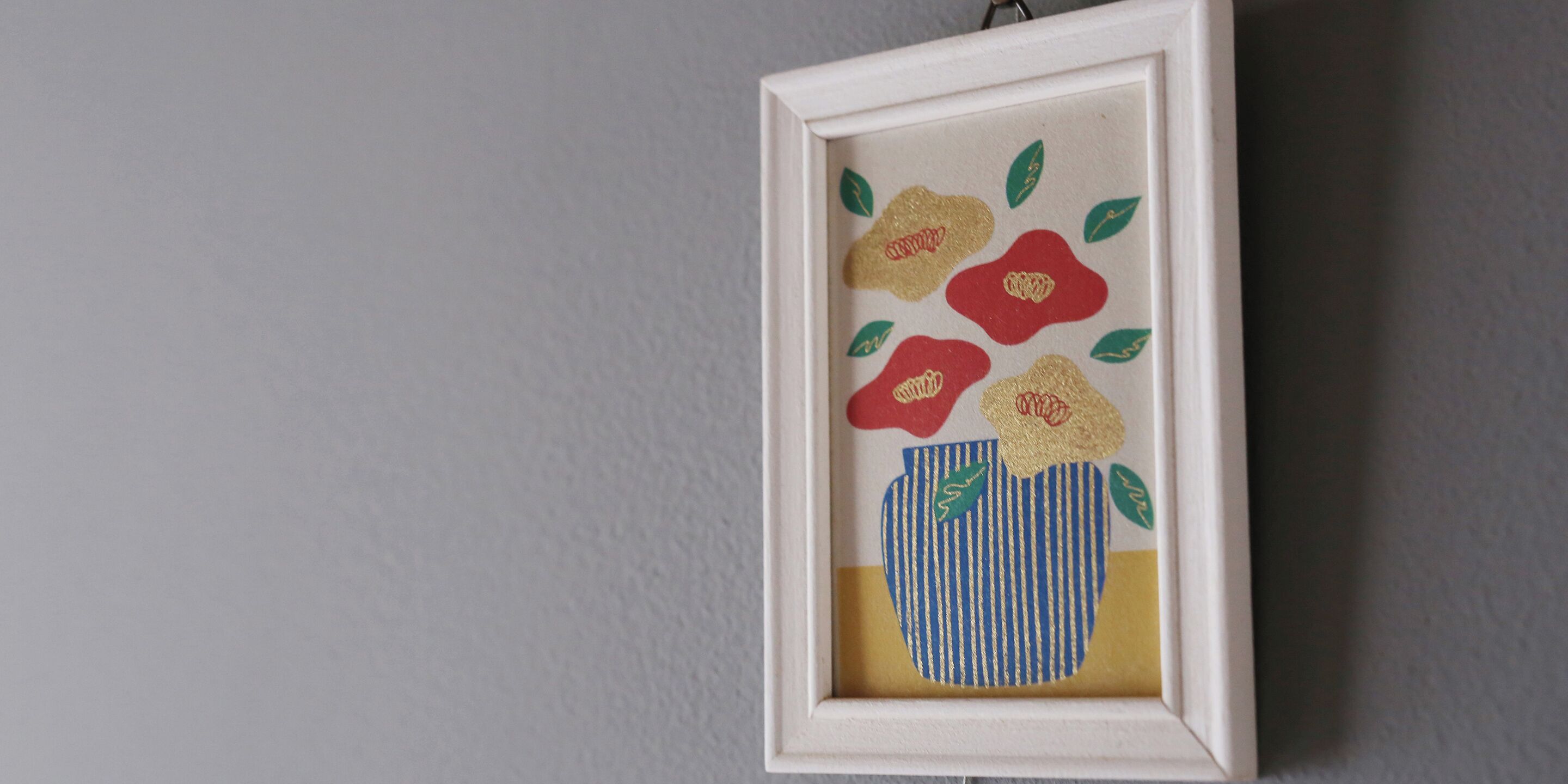 Una obra d'art emmarcada amb flors en un ram florit penjada a la paret.