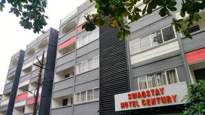 A multi-story hotel with a sign reading "SWAGSTAY HOTEL CENTURY".