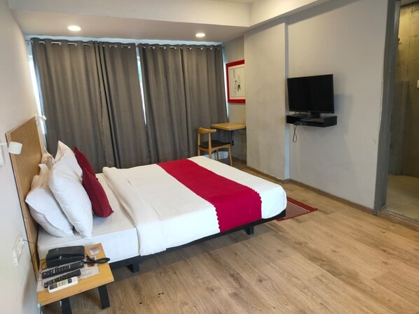 A hotel room with a bed, a TV mounted on the wall, a small table, and a chair. - SwagStay Hotel Century (Nagpur)