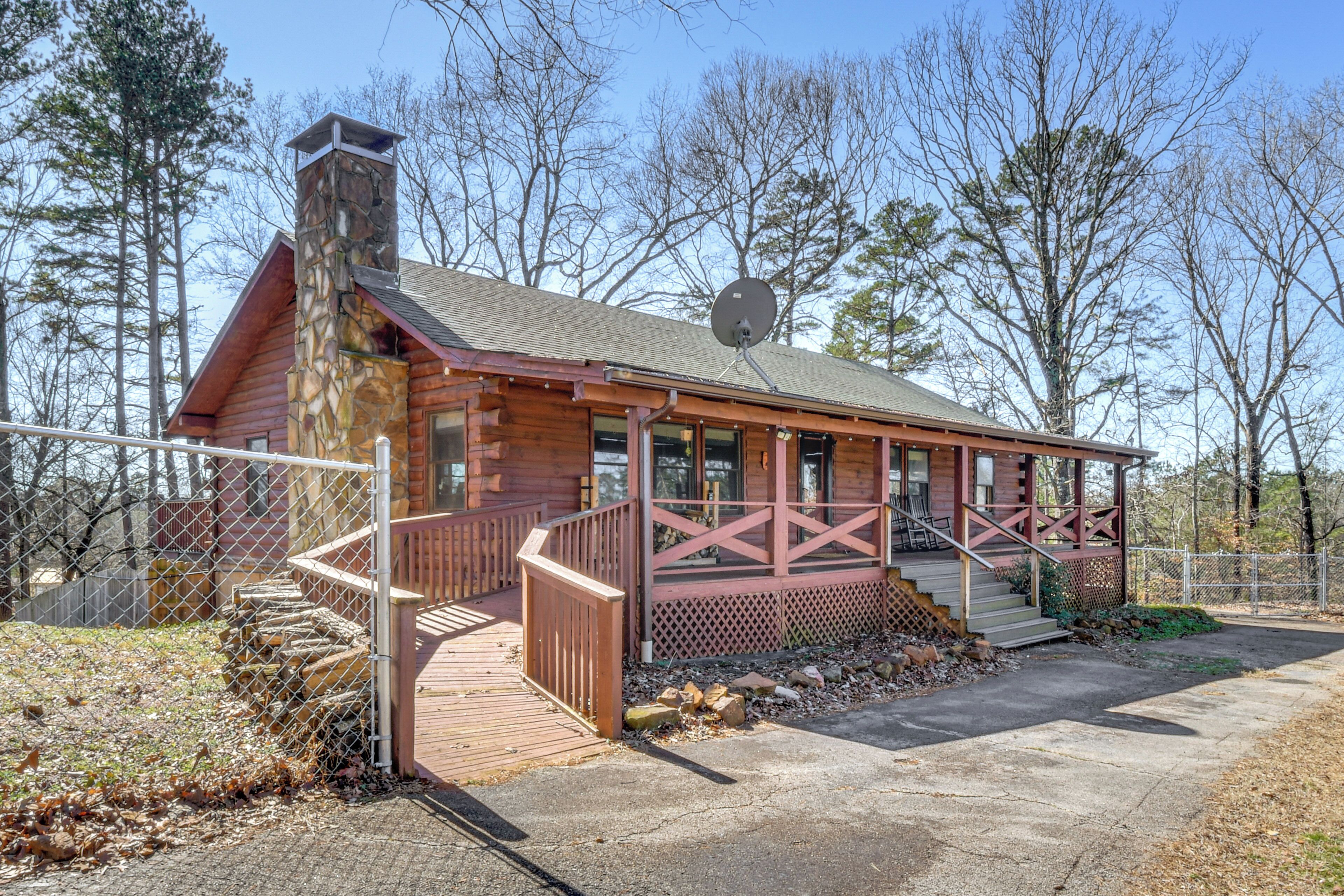 A log cabin with a stone chimney, a porch with railings, and a satellite dish.