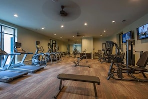 Un gimnasio con cintas de correr, elípticas y equipo de pesas.