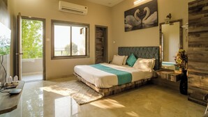 A modern bedroom with a large bed, a vanity with a mirror, and a view of greenery outside. - Polki Farm Resort Jawai -Sumerpur (Sumerpur)