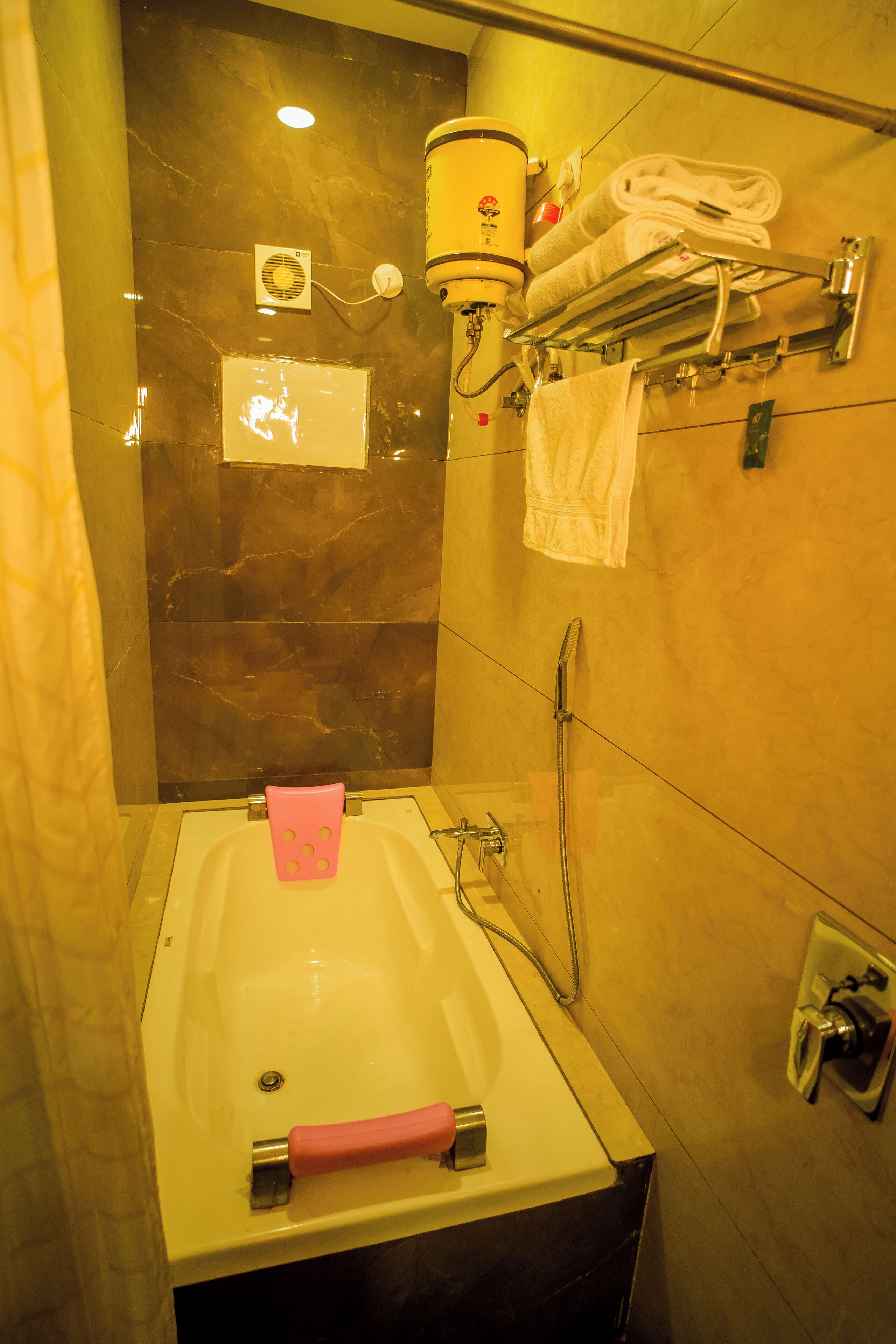 Une salle de bain avec une baignoire, un porte-serviettes avec des serviettes, un ventilateur et un radiateur.