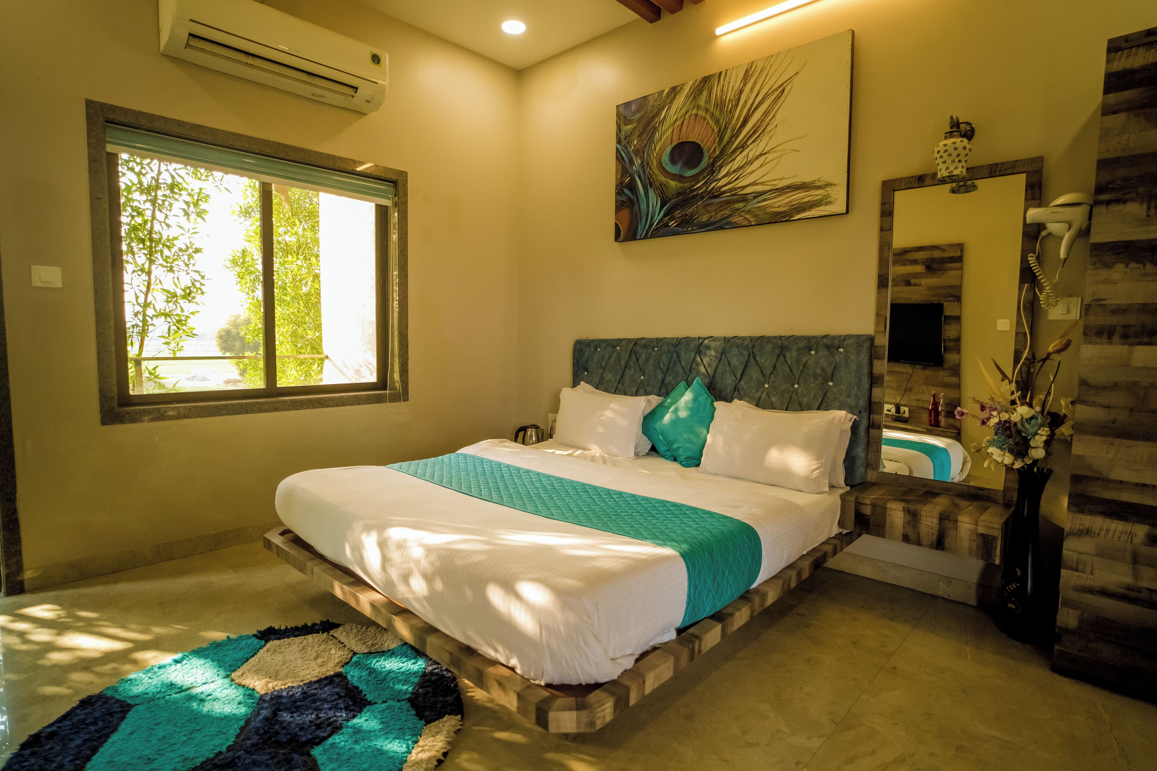 A bedroom with a large bed, a window, a mirror, and a wall-mounted air conditioner.