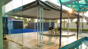 A covered outdoor area with a pool, seating, and a glass wall. - Polki Farm Resort Jawai -Sumerpur (Sumerpur)