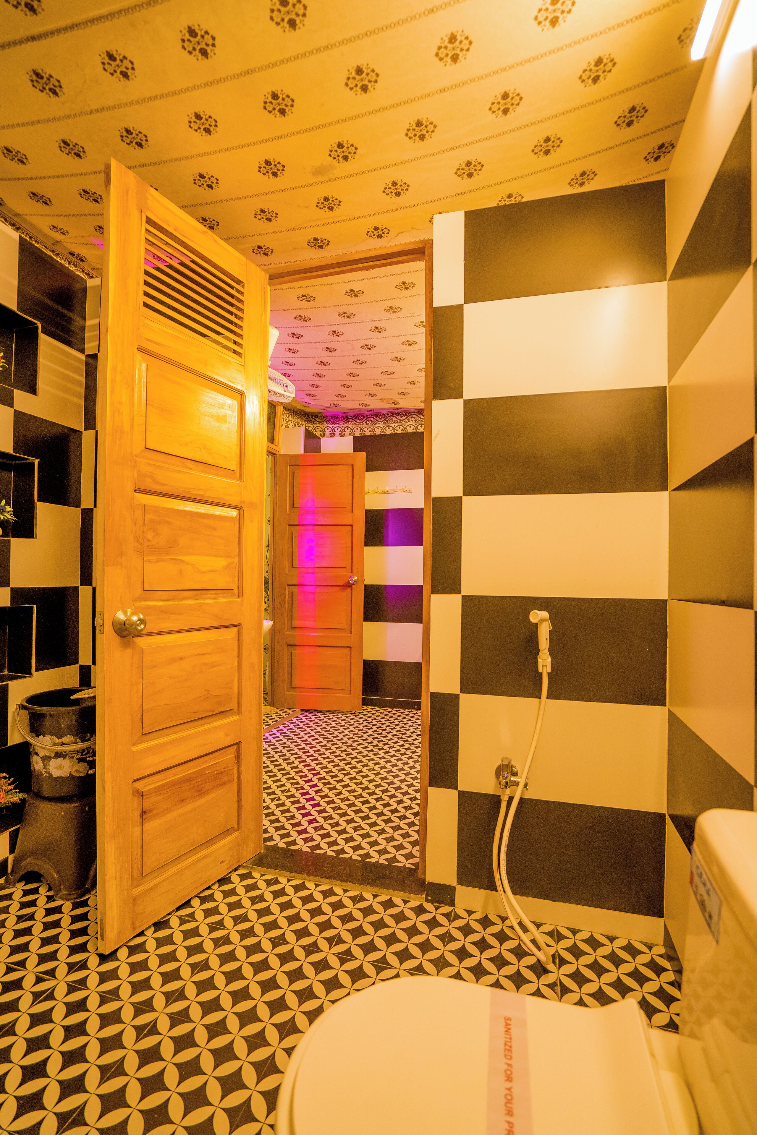 A bathroom with a checkered floor pattern, a wooden door, and a shower area.