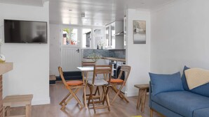 A compact living space with a dining area, a sofa, a TV, and a kitchen in the background. - Serene Cottage Nr the Waterfront, Topsham (Topsham)