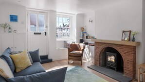 A living room with a fireplace, a sofa, a chair, and a bookshelf. - Serene Cottage Nr the Waterfront, Topsham (Topsham)