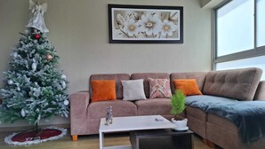 Un salon avec un sapin de Noël, un canapé, une table basse et un tableau encadré au mur.