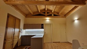 A compact kitchen with wooden cabinets, a countertop, and a ceiling with exposed beams.