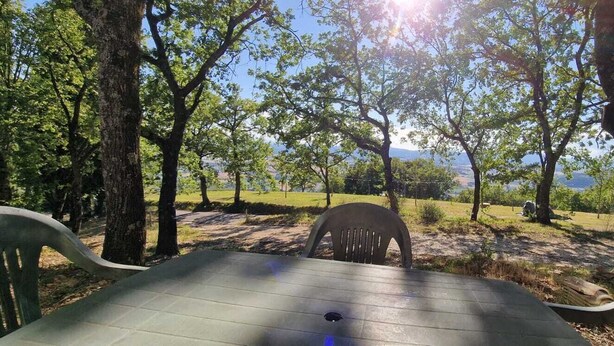 An outdoor table and chairs in a park with trees and a view of the landscape.