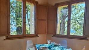 A dining area with a round glass table, white chairs, and wooden flooring.