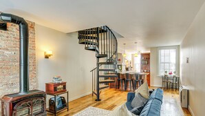 Ein Wohnzimmer mit Holzboden, einem blauen Sofa, einem Kamin und einer Wendeltreppe.