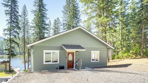 Une maison de plain-pied avec un toit en pente, un porche à l’avant et une allée gravillonnée.
