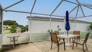 Un patio couvert avec une table et des chaises, un parasol bleu et une vue sur un quartier résidentiel.