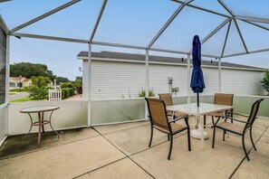 Un patio couvert avec une table et des chaises, un parasol bleu et une vue sur un quartier résidentiel.