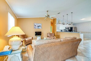 Un salon comprenant un canapé, des fauteuils, un téléviseur et un ventilateur de plafond.