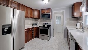A modern kitchen with stainless steel appliances, wooden cabinets, and a hexagonal tile floor. - Fish, Relax & Enjoy Lake Views: Colonial Beach Gem (Colonial Beach)