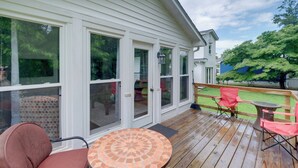 A covered deck with a round table and two chairs, large windows, and a view of a backyard. - Fish, Relax & Enjoy Lake Views: Colonial Beach Gem (Colonial Beach)