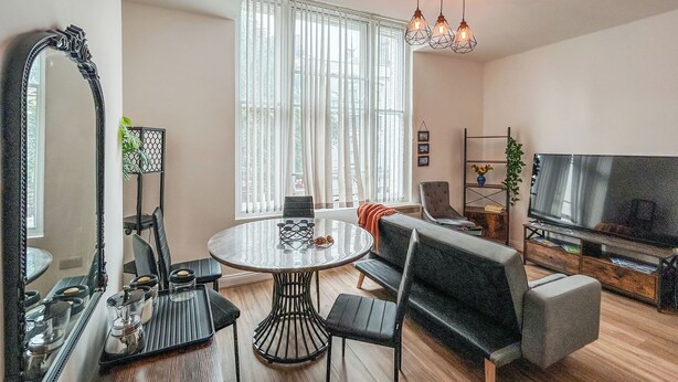 A modern living room with a round dining table, a sofa, a TV, and a large mirror.