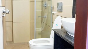 A bathroom with a toilet, sink, and shower. - The Executive Inn (Siliguri)