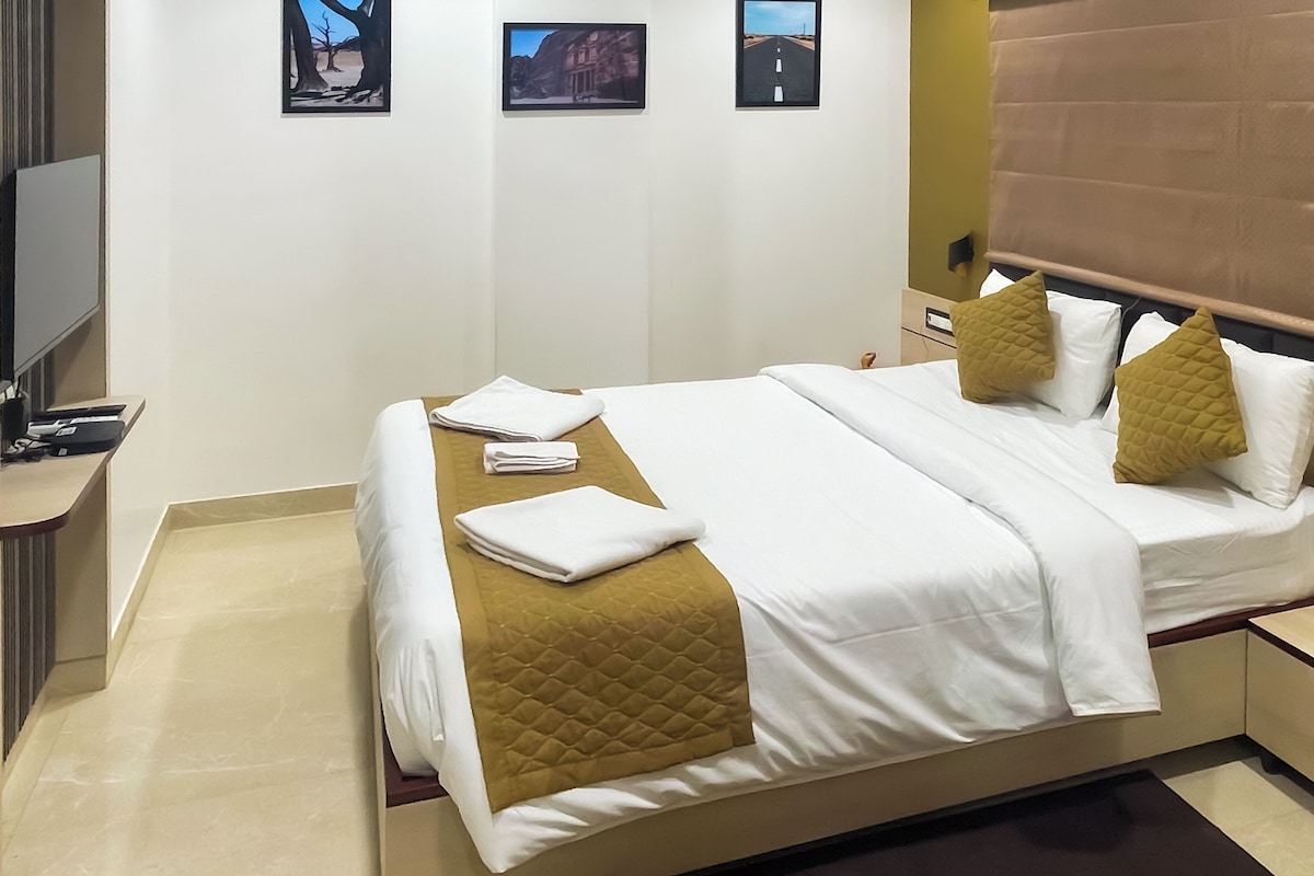 A hotel room with a bed, a desk, and a TV.