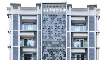 Un edificio de varios pisos con una fachada de diseño hexagonal característico, balcones y una entrada central.