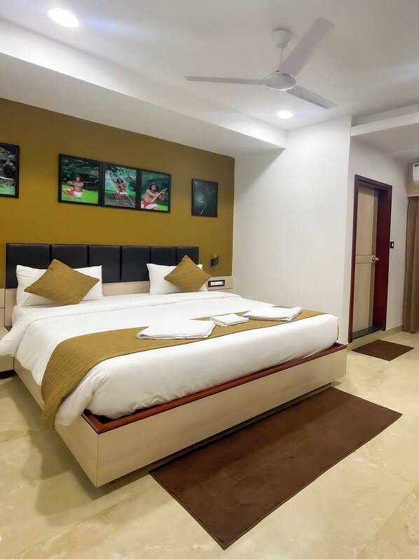 Une chambre d’hôtel avec un grand lit, un ventilateur de plafond et des œuvres d’art accrochées au mur.