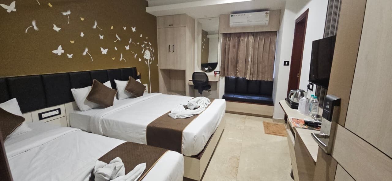 Ein Hotelzimmer mit zwei Betten, einem Schreibtisch, einem Fernseher und einem Badezimmer.
