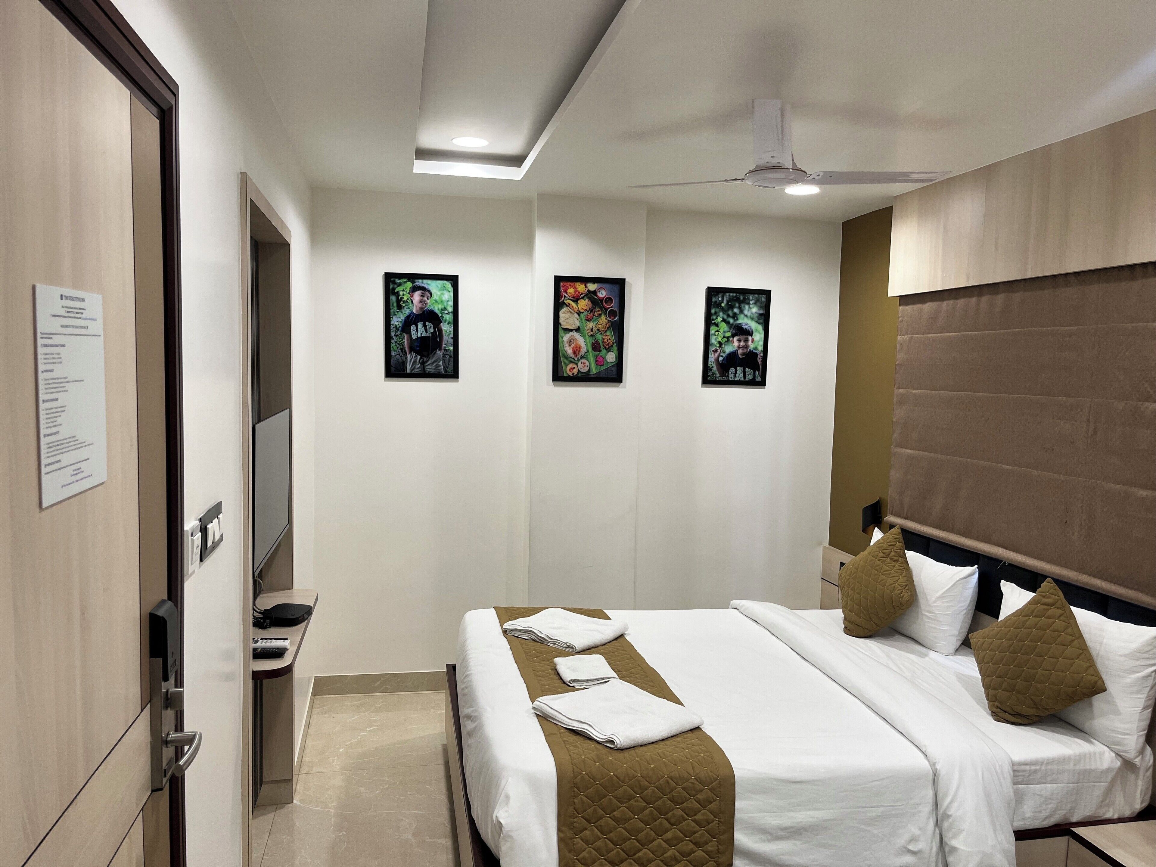 Ein Hotelzimmer mit einem Bett, einem Schreibtisch, einem Stuhl, einem Kleiderschrank und einem Deckenventilator.
