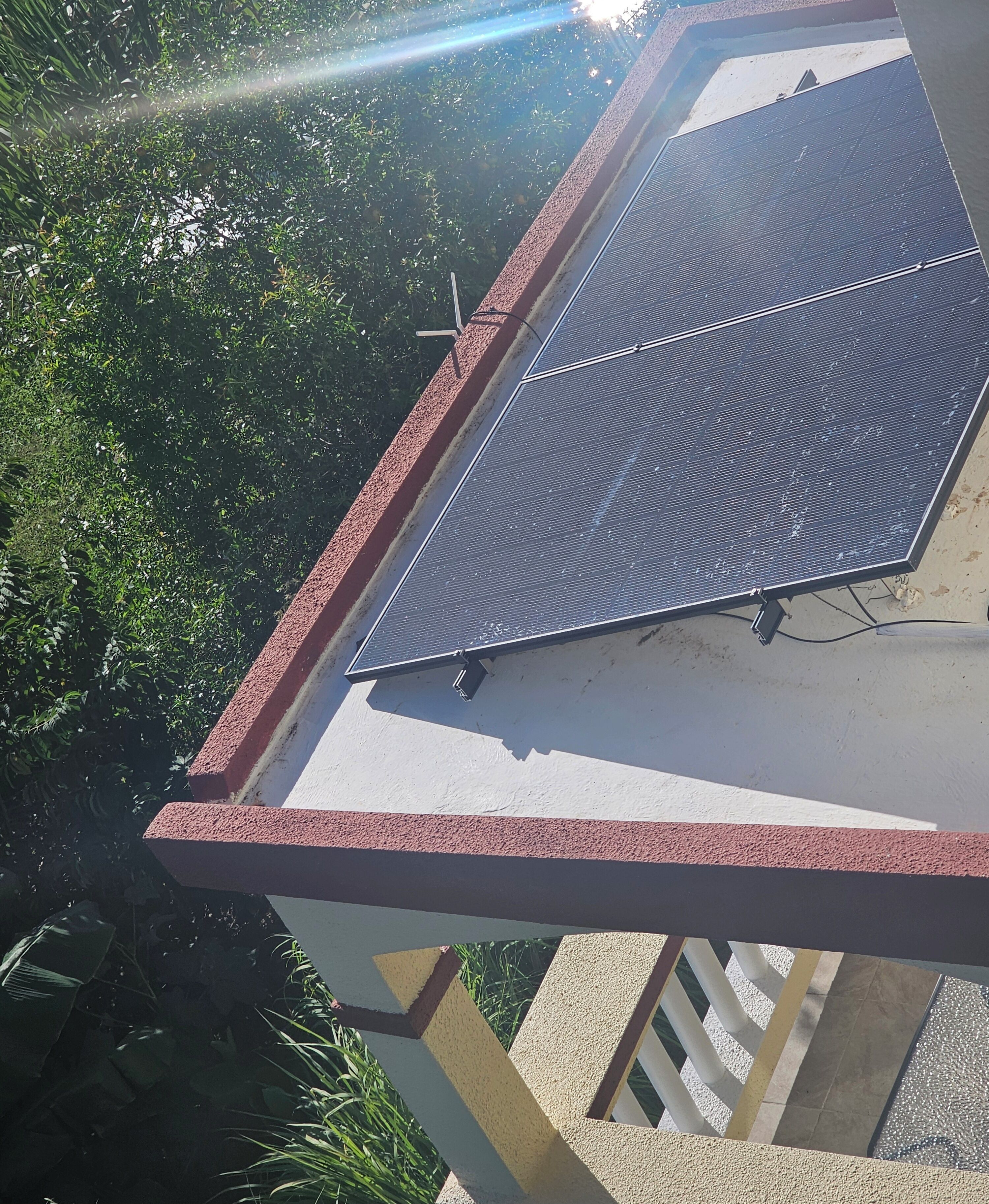 Un toit équipé de panneaux solaires et orné d’une rambarde rouge.