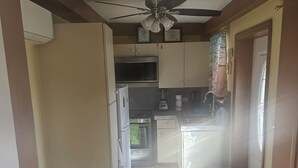 A compact kitchen with a ceiling fan, a microwave, a refrigerator, and a sink. - Baecation Romantic Getaway Couples & Singles (St. Thomas)