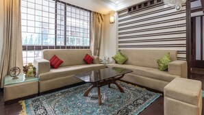 A living room with a sofa, a glass coffee table, and a patterned rug. - The Whispering Pines (Mussoorie)