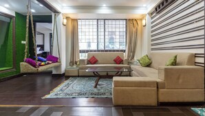 A modern living room with a sofa, a glass coffee table, and a hanging swing. - The Whispering Pines (Mussoorie)