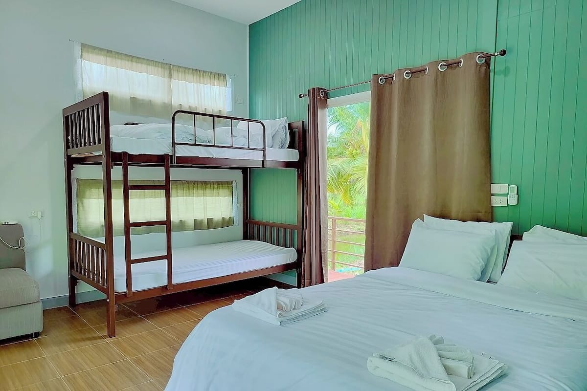 A room with a bunk bed, a single bed, and a sofa.