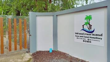 A gated entrance with a signboard displaying a logo and contact information.