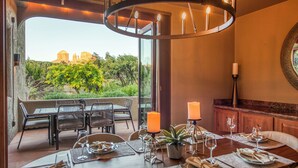 Un comedor con vista a un paisaje natural, una araña y una vela sobre la mesa.