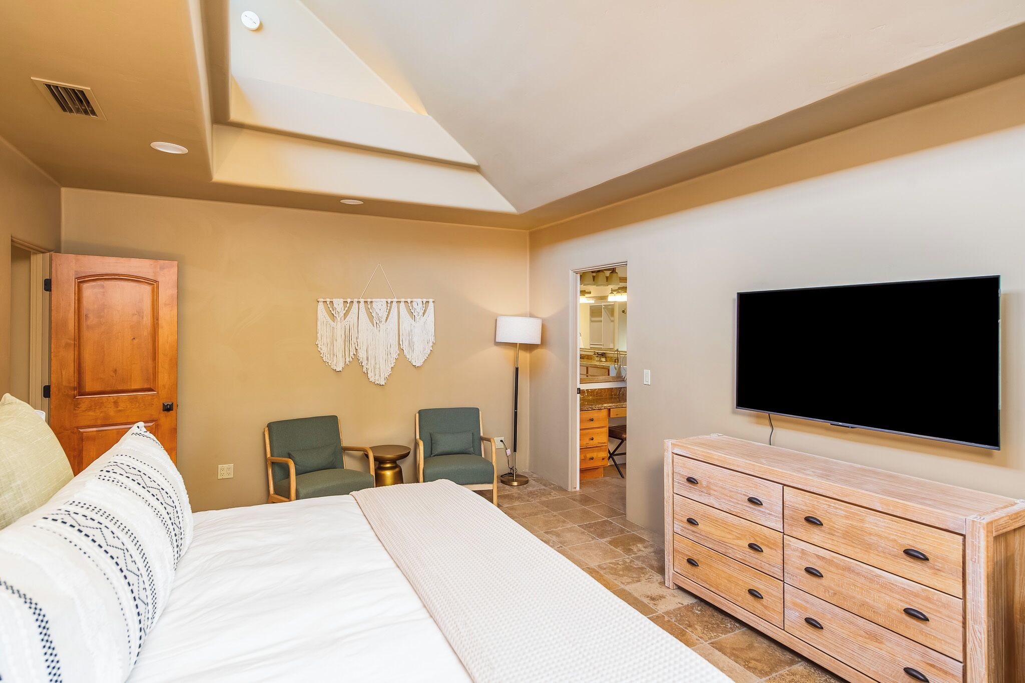 A hotel room with a bed, a TV, a desk, and a chair.