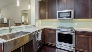 A modern kitchen with dark wooden cabinets, stainless steel appliances, and a light-colored backsplash. - Comfort at the Star I 2 Bed Apt in Houston (Houston)