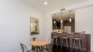 A dining area with a round table and six chairs, a kitchen with modern appliances, and pendant lighting. - Comfort at the Star I 2 Bed Apt in Houston (Houston)