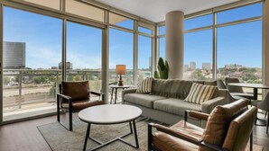 A spacious living area with a large window, a sofa, a coffee table, and leather chairs.
