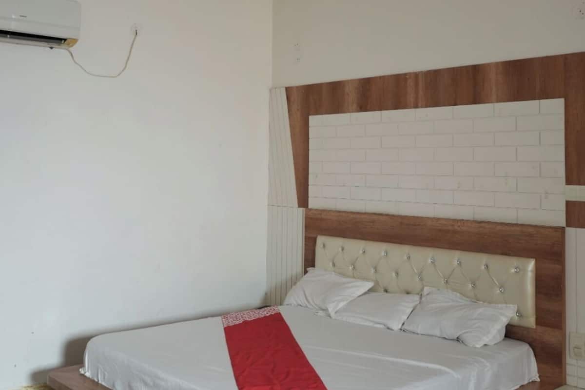 Un dormitorio moderno con cabecera de madera, ventilador de techo y aire acondicionado.