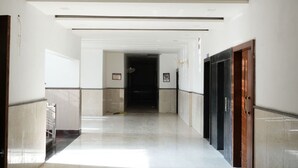 A long, narrow hallway with a tiled floor and a series of doors on one side.